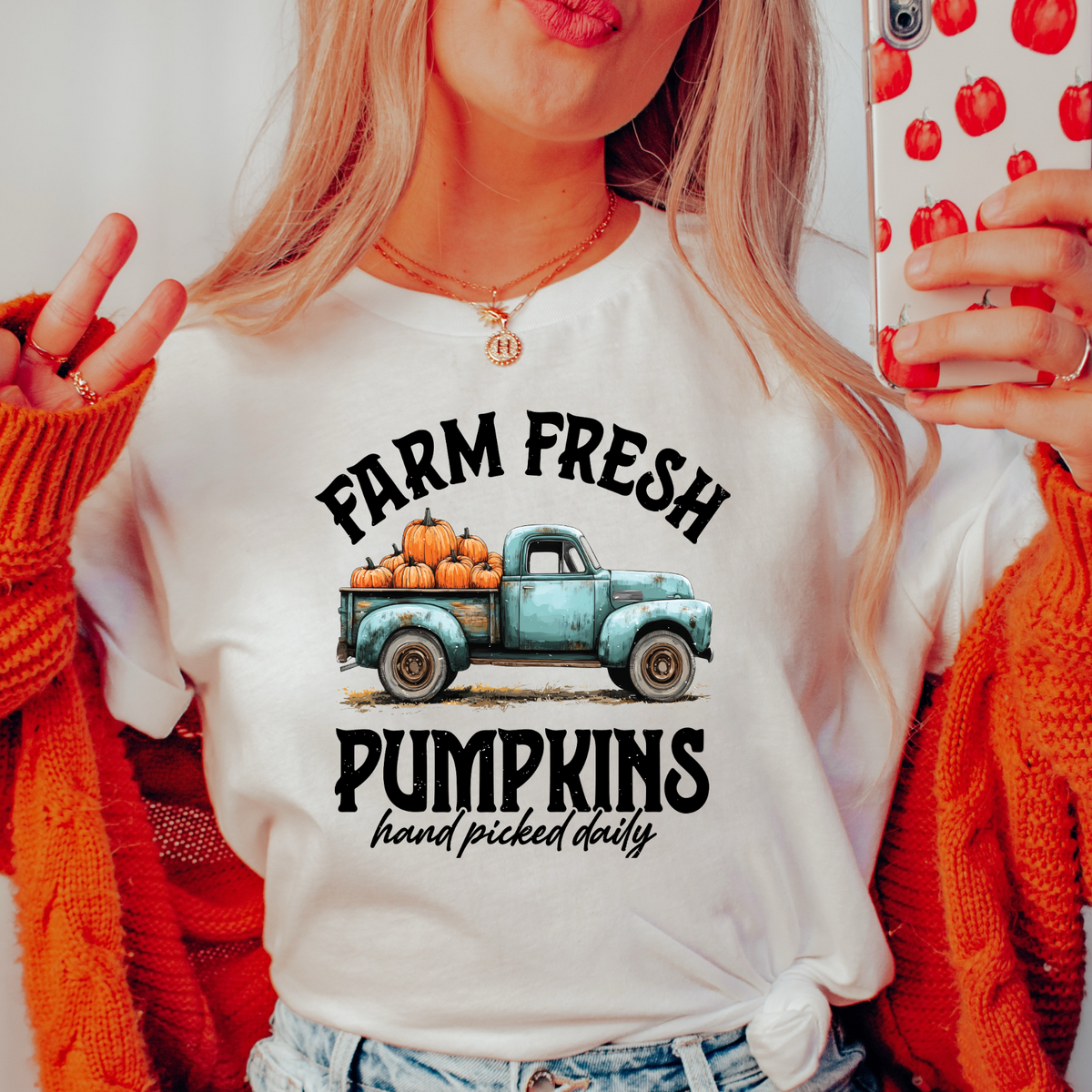 Person wearing a white t-shirt with 'Farm Fresh Pumpkins' graphic design.